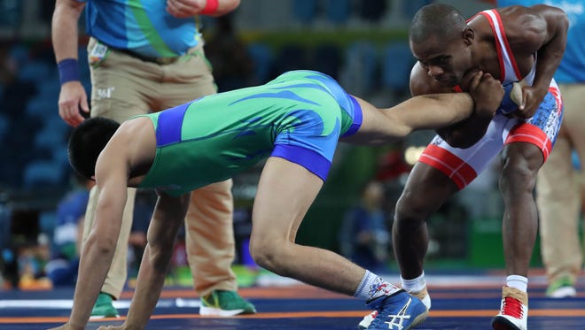 Yowlys Bonne Rodriguez of Cuba faces Abbos Rakhmonov of Uzbekistan during men's freestyle wrestling competition in the Rio 2016 Summer Olympic Games at Carioca Arena 2.