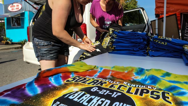 Jenn Sugg, right, and Laura Collins, left, put out t-shirts commemorating the solar eclipse at the Summer Salute in Hopkinsville.