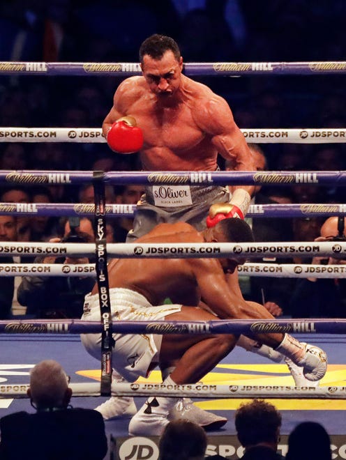British boxer Anthony Joshua, front, is knocked down by Ukrainian boxer Wladimir Klitschko as they fight for Joshua's IBF and the vacant WBA Super World and IBO heavyweight titles at Wembley stadium.