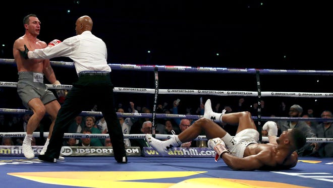 British boxer Anthony Joshua, right on the ground as Ukrainian boxer Wladimir Klitschko  is held back, during the fight for Joshua's IBF and the vacant WBA Super World and IBO heavyweight titles, at Wembley Stadium.