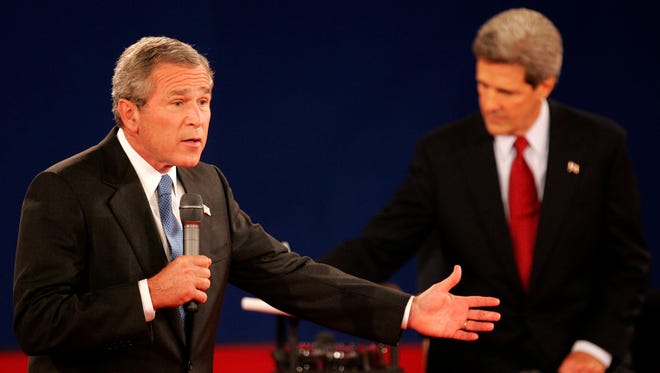 Bush answers a question as Kerry takes notes during their debate in St. Louis on Oct. 8, 2004.