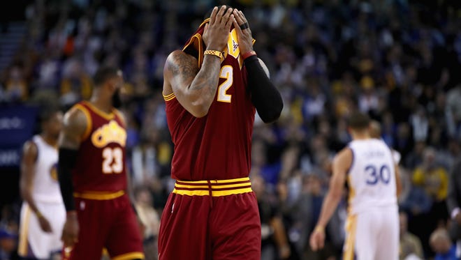Kyrie Irving of the Cleveland Cavaliers wipes his face as he walks to the bench for a time out during their game against the Golden State Warriors.