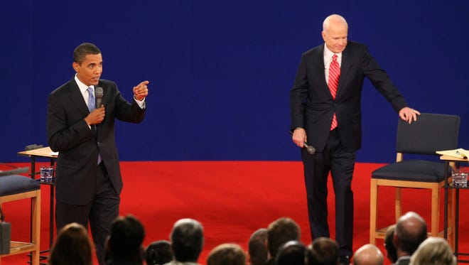 Obama answers a question as McCain listens in the background during their debate at Belmont University in Nashville, Tenn., on Oct. 7, 2008.