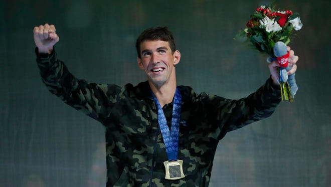 Michael Phelps celebrates at the medal ceremony after winning the men's 100m butterfly final at the U.S. Olympic swimming team trials.