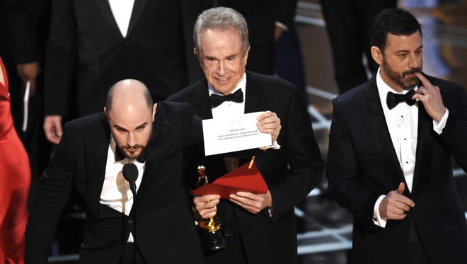 'La La Land' producer Jordan Horowitz shows the envelope revealing "Moonlight" as the true winner of best picture at the Oscars, as presenter Warren Beatty and host Jimmy Kimmel look on.