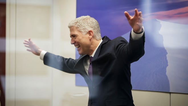 Gorsuch, seen through glass, makes an animated gesture while speaking with staff members before his meeting with Sen. Tom Udall, D-N.M., on Feb. 27, 2017, on Capitol Hill.