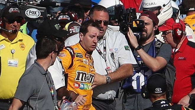 Officials escort Kyle Busch from pit road after a physical altercation with Joey Logano's pit crew.