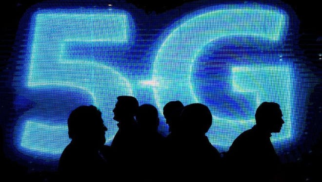 Visitors walk past a 5G logo during the Mobile World Congress on the third day of the MWC in Barcelona, on March 1, 2017.
