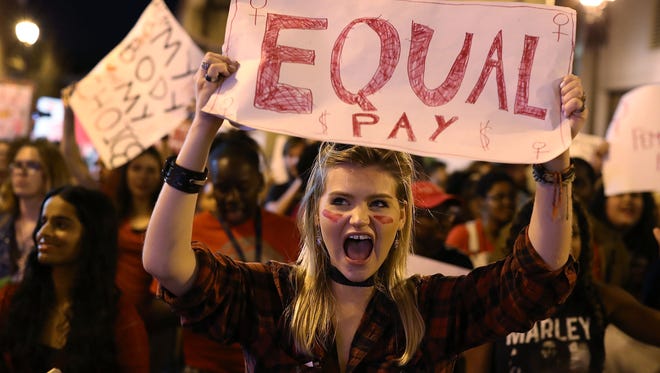 Clarissa Horsfall holds a sign reading, 'Equal Pay,' as she joins with others during 'A Day Without A Woman' demonstration on March 8, 2017 in Miami. Some states and cities are barring employers from asking job candidates their prior salaries to promote pay equity between men and women.