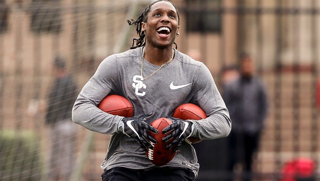 Southern California's cornerback and return specialist Adoree' Jackson smiles before catching a punt while already holding three footballs during the team's NFL football pro day in Los Angeles, Wednesday, March 22, 2017.