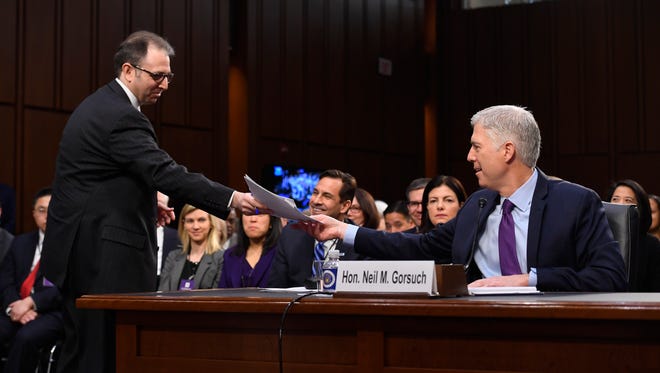 A Senate staff member hands documents to Gorsuch during Day Two of his confirmation hearings before the Senate Judiciary Committee on March 21, 2017.