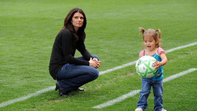 U.S. soccer great Mia Hamm, plays with one of her twin daughters in 2009. The twins, Grace and Ava, also have a younger brother, Garrett.