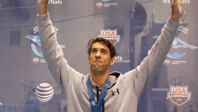 Michael Phelps waves to the crowd after winning the 200-meter butterfly finals at the AT&T Winter National Championships at the Weyerhaeuser King County Aquatic Center.