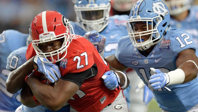 Georgia Bulldogs running back Nick Chubb (27) runs the ball against North Carolina Tar Heels linebacker Andre Smith (10) and defensive end Tomon Fox (12) during the first quarter of the 2016 Chick-Fil-A Kickoff game at Georgia Dome.