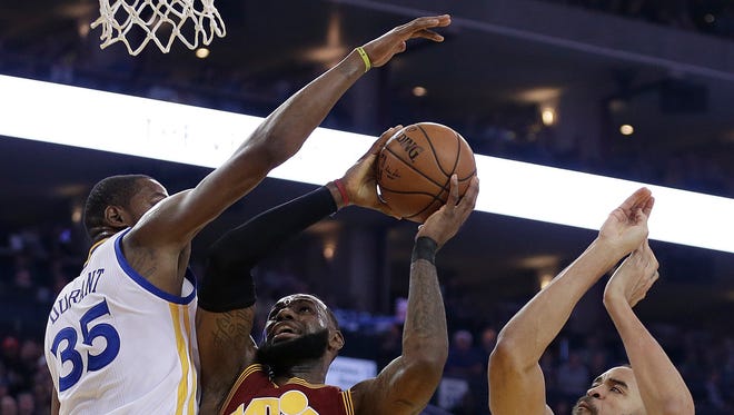 LeBron James shoots between Kevin Durant and JaVale McGee during the first half.