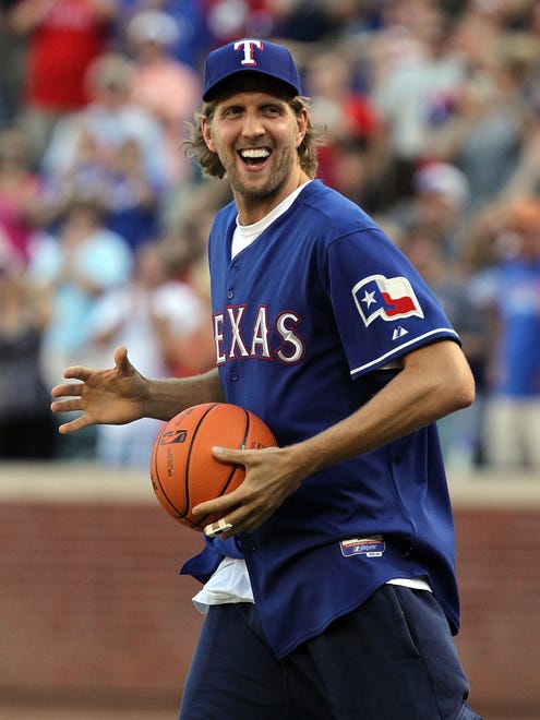 2011: Dirk Nowitzki of the Dallas Mavericks carries a basketball before throwing out the ceremonial first pitch.
