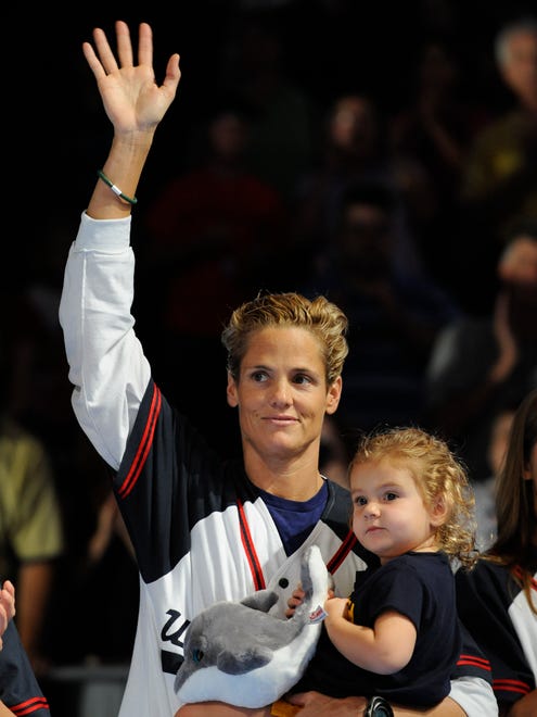 Olympic gold medal-winning swimmer Dara Torres waves to the crowd while holding her daughter, Tessa.