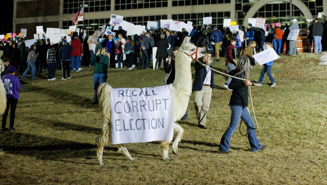 A woman walks a llama as people take part in a protest outside Raritan Valley Community College before a town hall meeting on health care with Rep. Leonard Lance, R-N.J., on Feb. 22, 2017, in Branchburg, N.J.