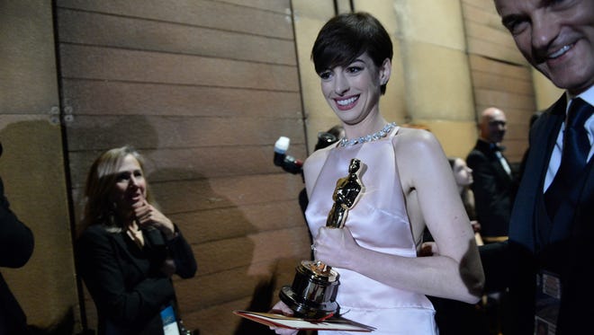 The winners and their Oscars take a " winner ' s walk. " Excited winners (pictured: Anne Hathaway in 2013) might be offered a chair or a bottled water. They then head down a corridor filled with pictures of past winners, to meet the blinding lights of the photographers.