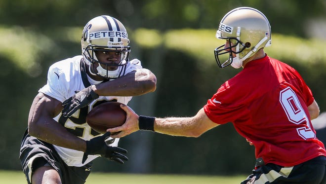 New Orleans Saints quarterback Drew Brees (9) hands the ball off to running back Adrian Peterson (28) during organized team activities at the New Orleans Saints training facility.