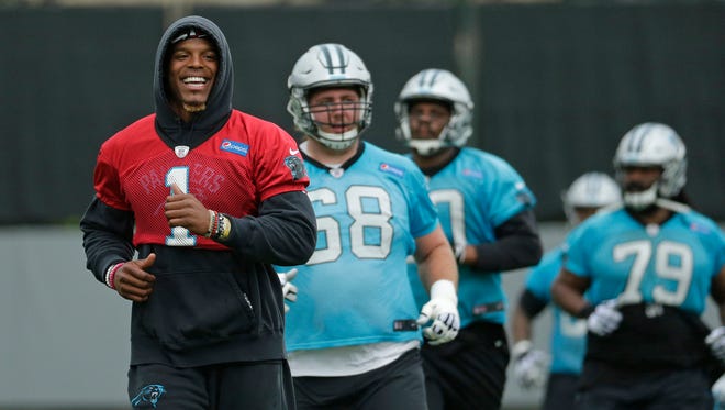 Carolina Panthers quarterback Cam Newton smiles as he runs past teammates during the NFL football team's organized team activity in Charlotte, N.C., Thursday, May 25, 2017.