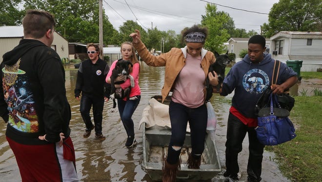 Destiny Harris is helped out of a boat by Tyshon Sykes at the Village Green Estates trailer park on May 1, 2017, in Cedar Hill, Mo. after torrential rains over the weekend caused flash flooding across Missouri.