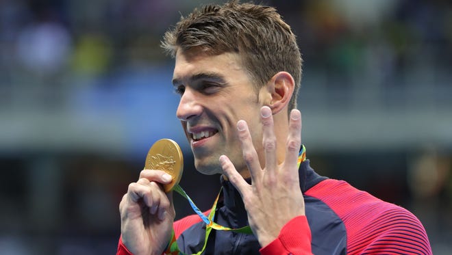 Michael Phelps holds up four fingers, for his fourth gold of the Rio Games, after winning the men's 200-meter individual medley.