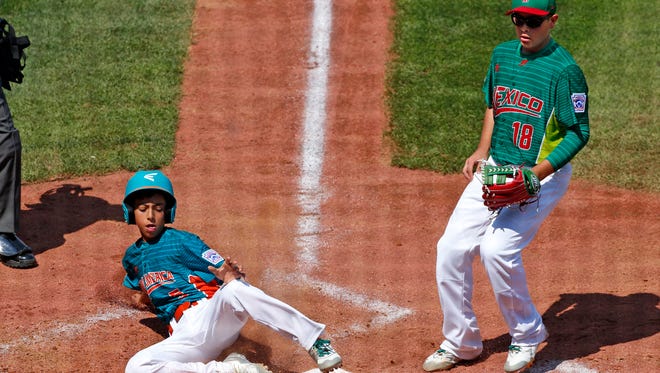 Venezuela's Jhann Bozo, left, scores from third on a wild pitch by Mexico pitcher Jorge Garcia (18).