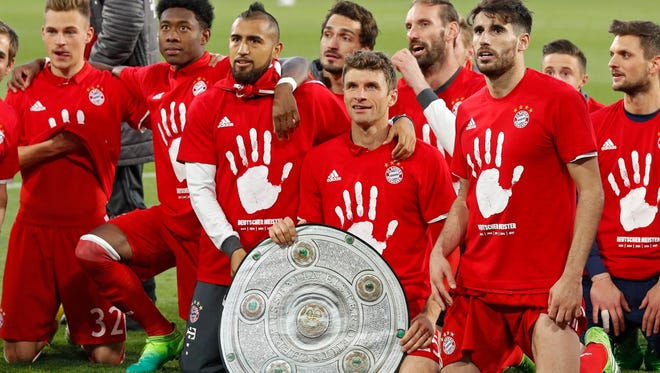 Bayern Munich players celebrate with a mock paper Bundesliga championship trophy after winning the Bundesliga.
