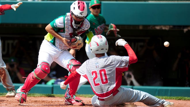 Japan runner Natsuki Yajima (20) slides across the plate to score past Mexico catcher Jorge Lambarria (15) during the first inning of the International championship game.