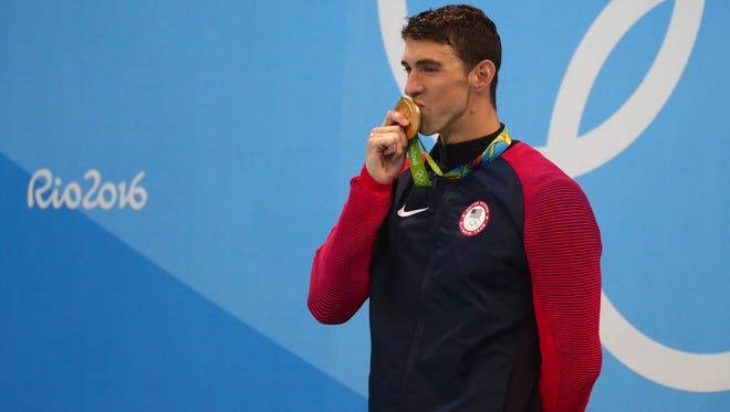 Michael Phelps celebrates with his gold medal on the podium after the men's 200-meter butterfly. It was the 20th gold of Phelps' career.