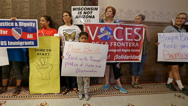 Five-year-old Kevin Trujillo (center) of Milwaukee holds a sign aimed at Mayor Tom Barrett as others hold signs as well. The group held a news conference last month to address issues concerning changes made to the Milwaukee Police Departments policy for dealing with immigrants.