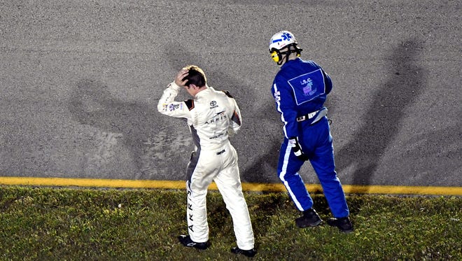 Carl Edwards, left, dejectedly walks to the infield care center after crashing with 10 laps remaining in Sunday's championship race.