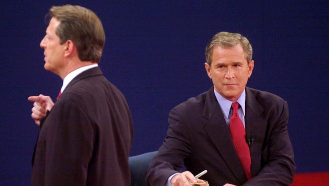 Bush listens while Gore answers a question during their town hall-style debate at Washington University in St. Louis on Oct. 17, 2000.